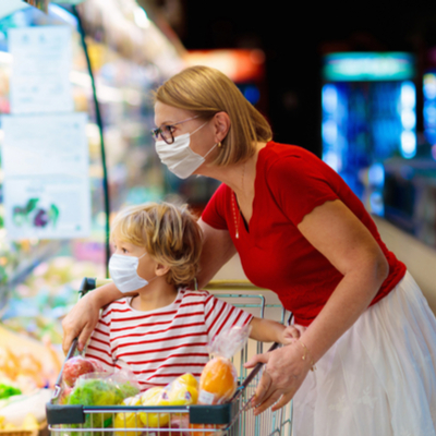 Woman and child shopping at grocery store in masks