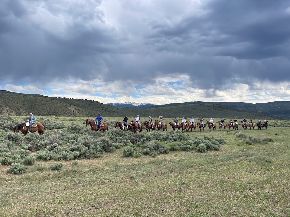 Program attendees riding horseback in a line across a field