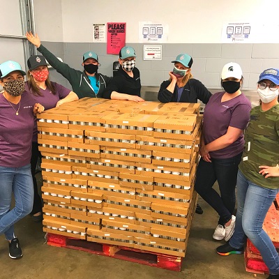 Group of masked people around pallets of canned goods.