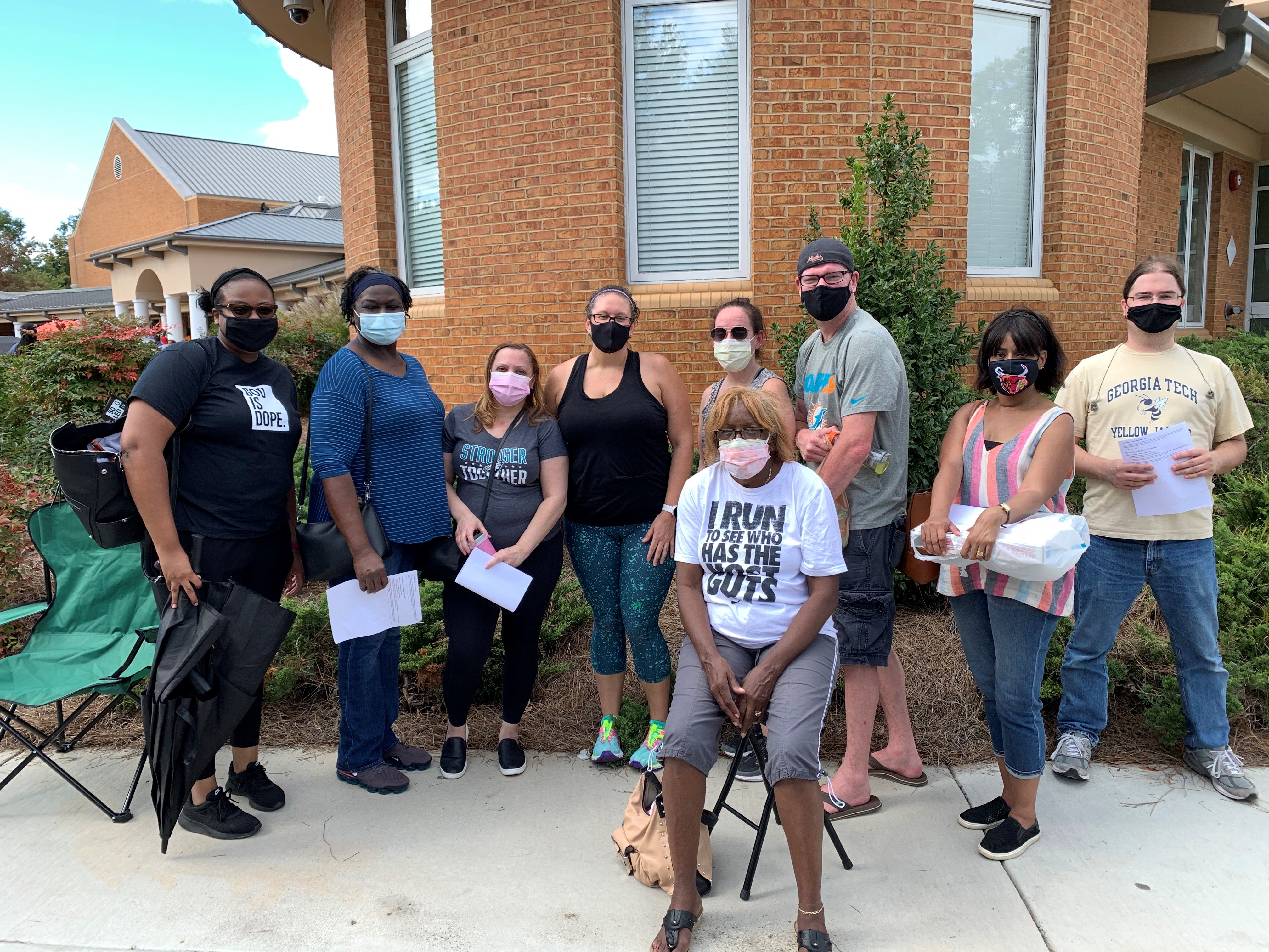 Group of people in masks waiting in line to vote.