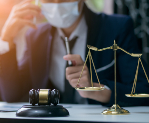 Man in mask sitting behind sales of justice.