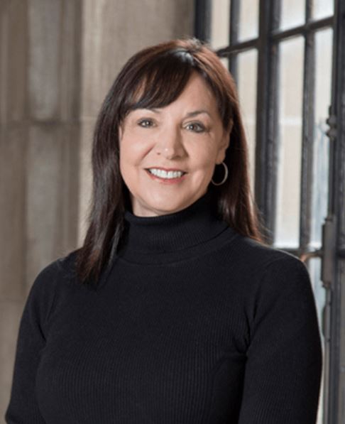 Elizabeth Govaerts wearing a black turtleneck shirt in front of a window.
