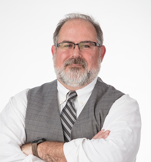 Martin Crump wearing a white collared shirt and vest.