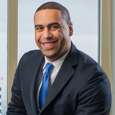 N John Bey in a black suit with blue tie