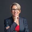 Laura Yaeger, woman with short hair, glasses, and light blazer.