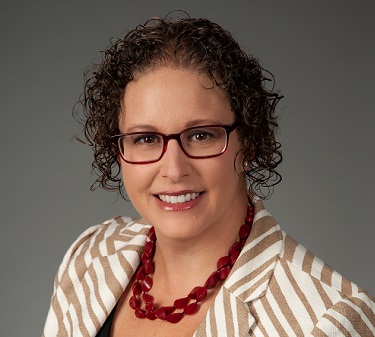 Sharon Zinn wearing a blazer and red necklace.