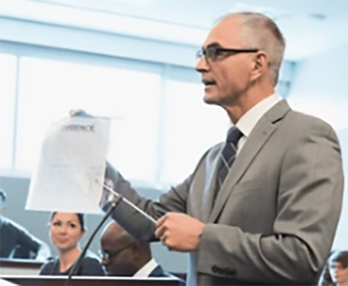 attorney holding document in front of jury in courtroom