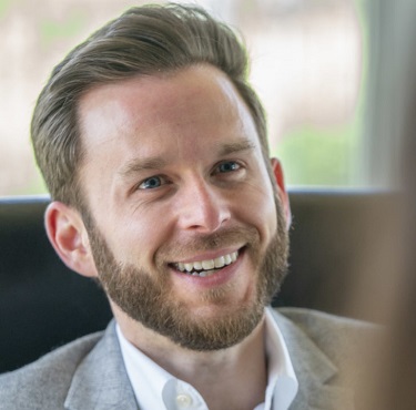 Ben Cooper headshot, man with short hair, beard and light suit