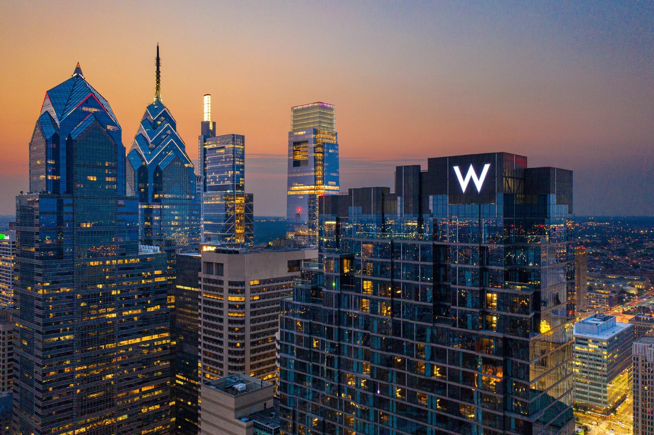 The W Philadelphia Hotel, lit at sunset with the Philadelphia skyline behind it