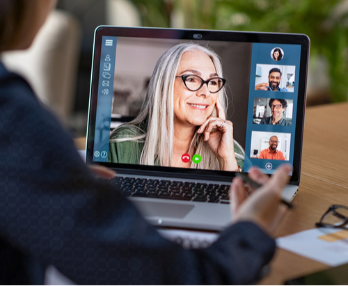 Laptop with a video deposition screen featuring a woman with glasses and three smaller panels on the right